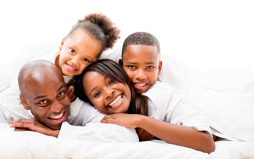 Beautiful family portrait lying in bed and smiling - isolated over white